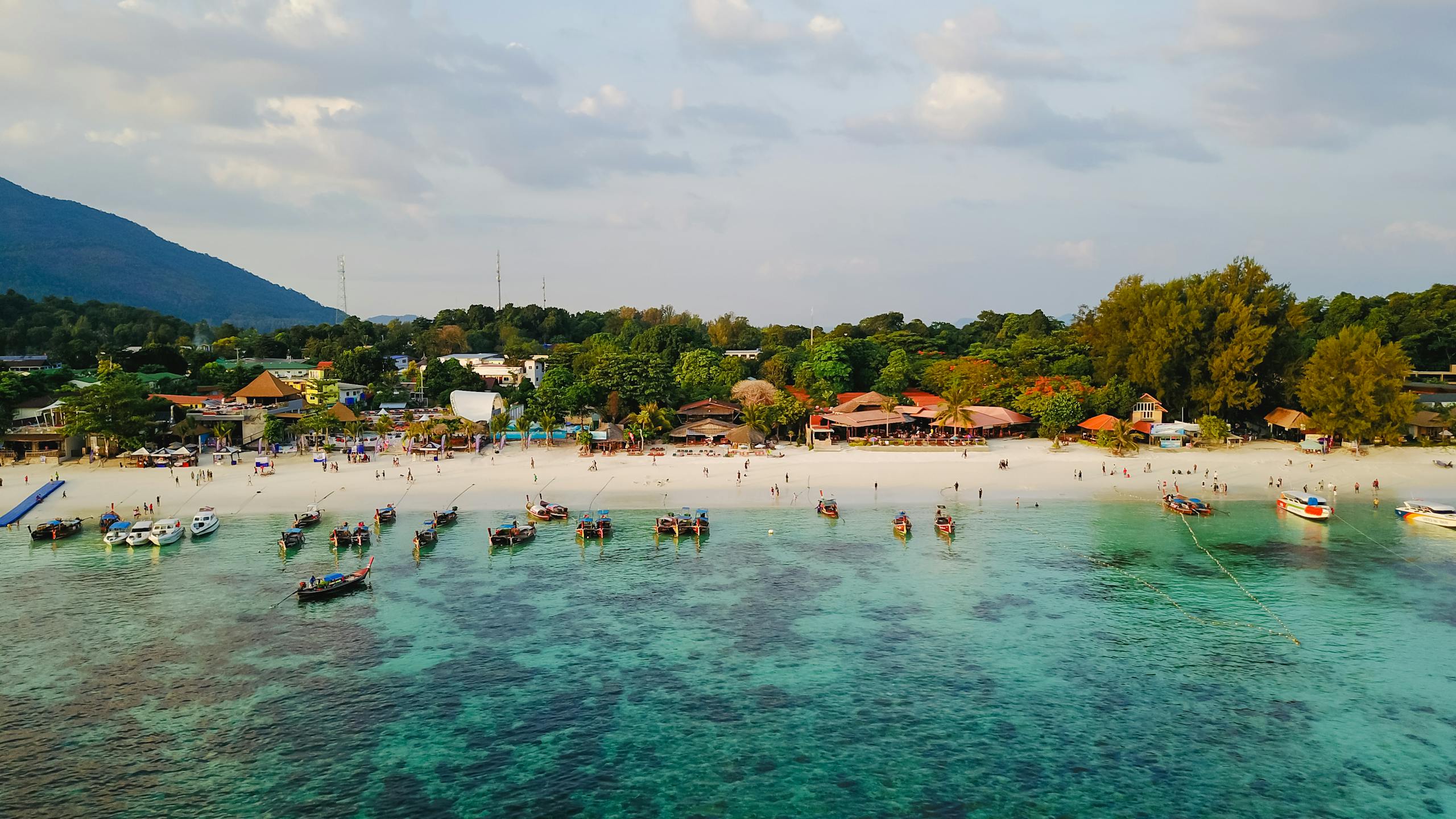 A beautiful aerial view of a tropical beach with boats and lush greenery, ideal for vacation.
